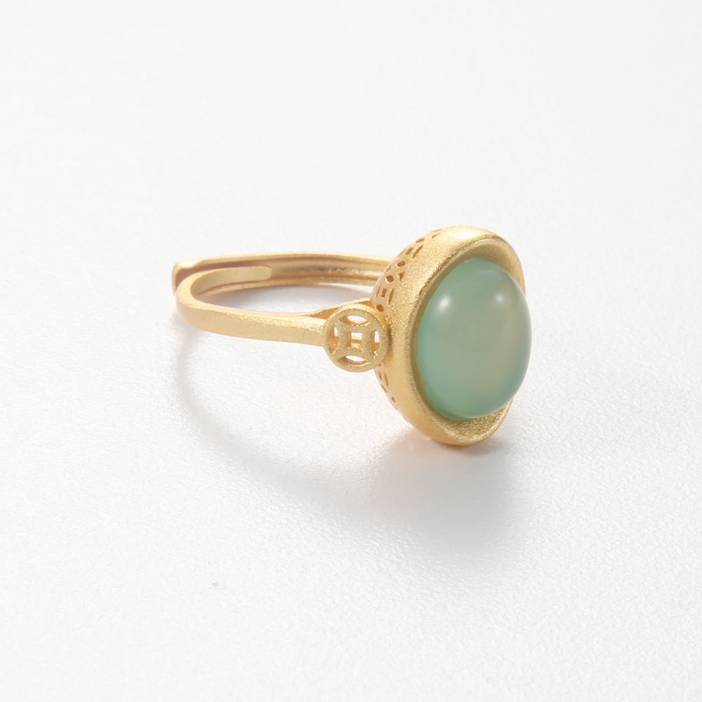 Gold tone ring in the shape of a Chinese Yuan Bao ingot, set with a light green gemstone and featuring ancient coin, symbolizing wealth and good fortune.