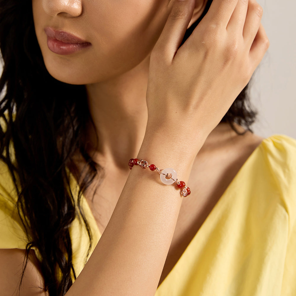 Woman wearing lucky red beaded bracelet with white jade and butterfly charm.