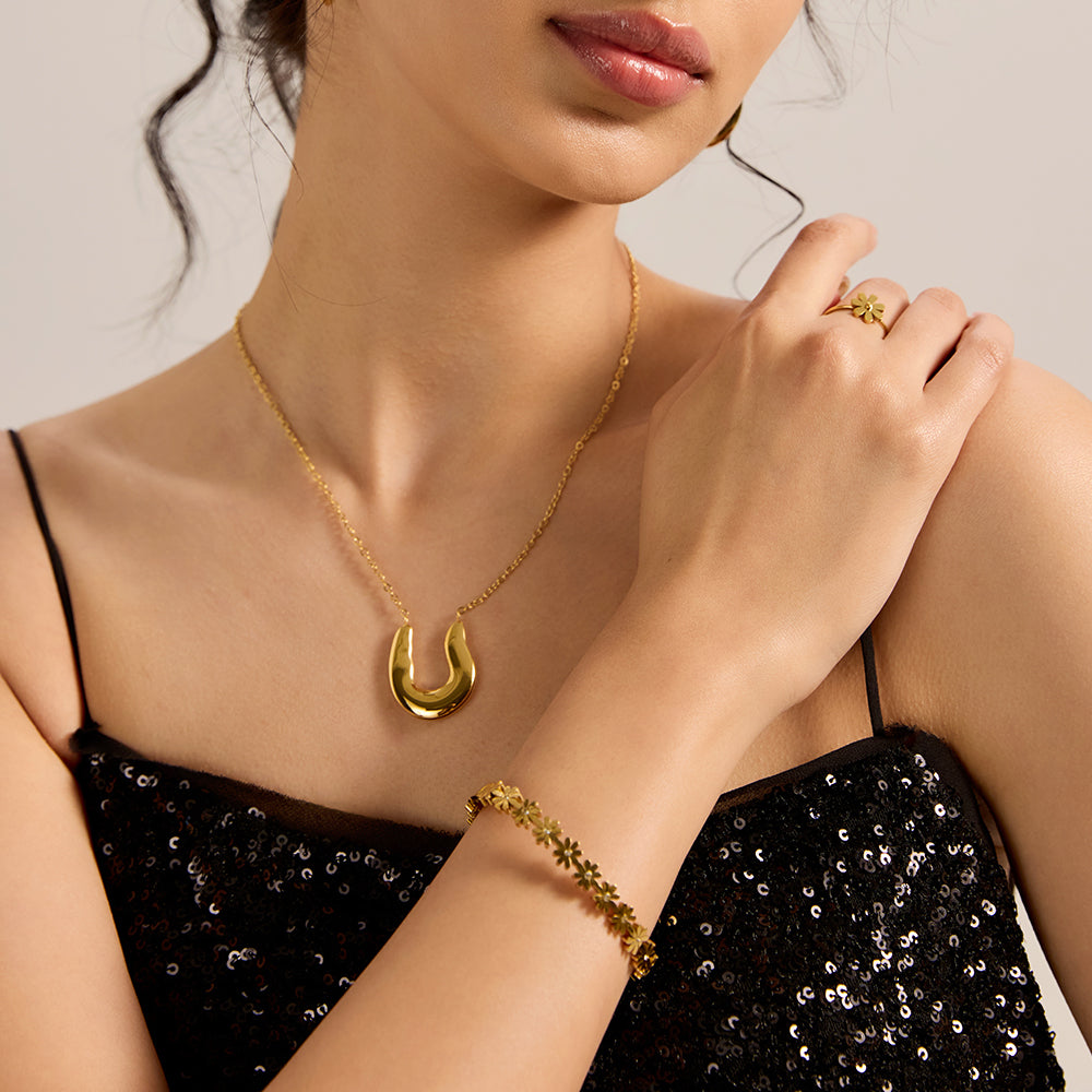 Close-up of woman's wrist wearing gold daisy chain bracelet, showcasing its elegant floral design.
