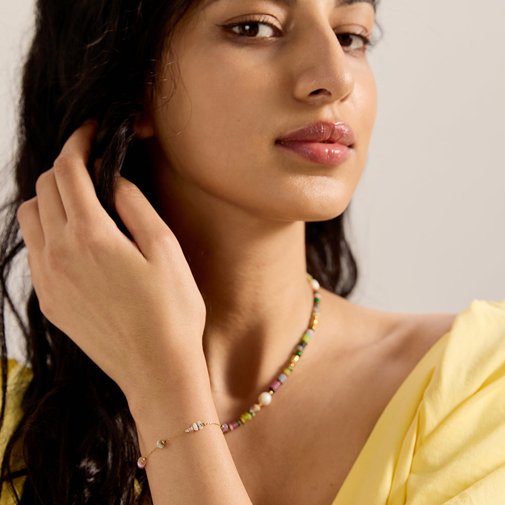 Side view of model's hand showcasing colorful beaded gold chain bracelet on wrist