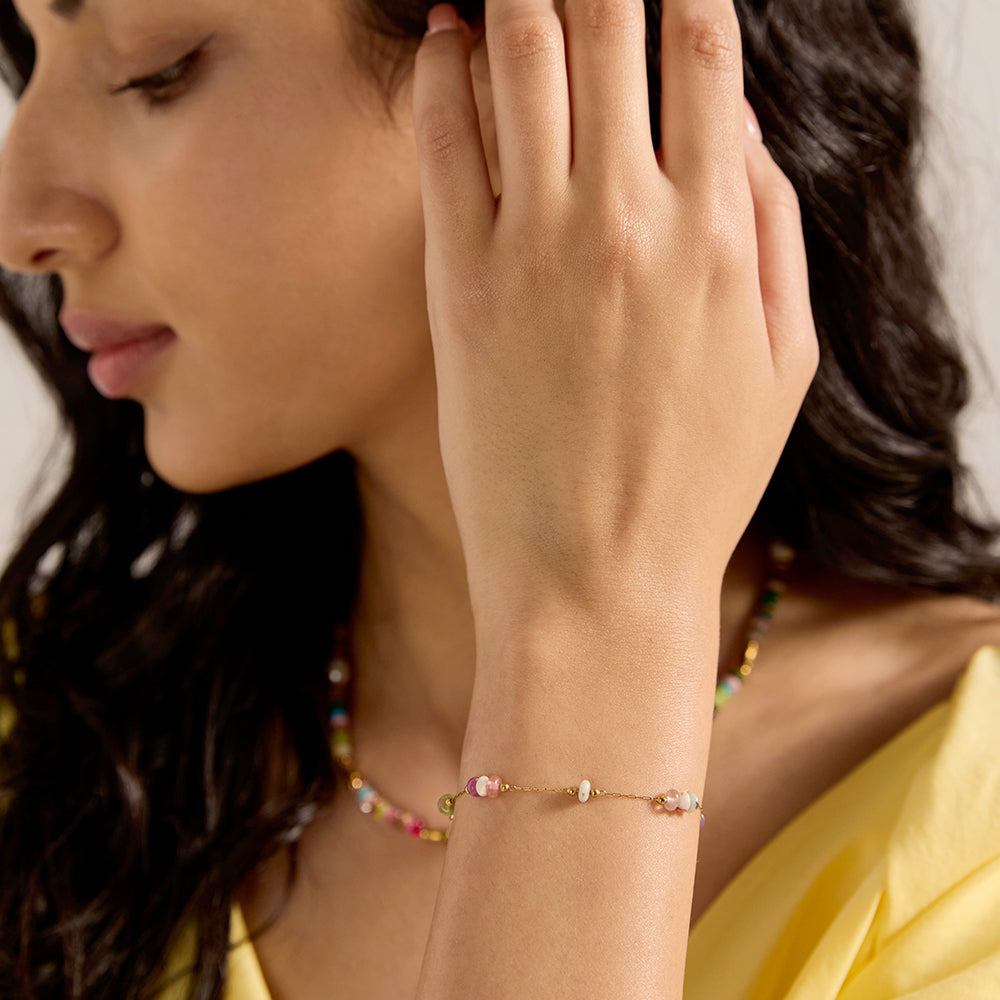 Model wearing vibrant colorful beaded gold chain bracelet and matching necklace, enhancing a summer outfit.