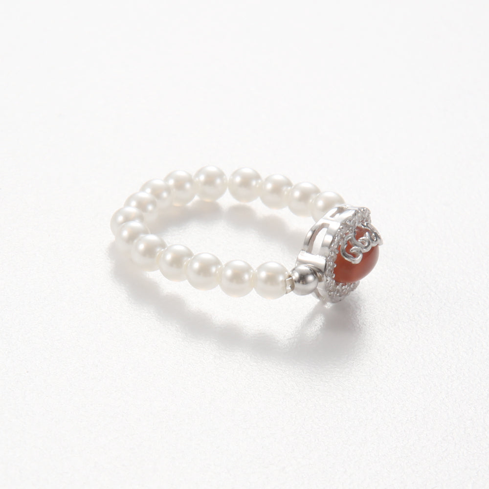 Side view of the pearl beaded elastic ring, showing the arrangement of pearls and the detailed setting of the central red-orange stone.