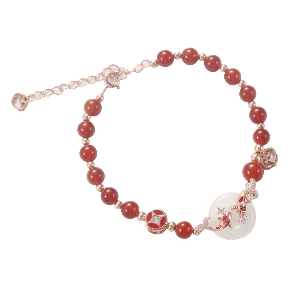 Close-up of red beaded bracelet showing white jade-like stone on wrist.