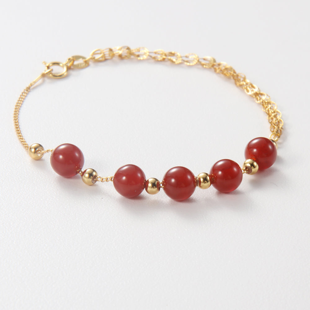 Radiant red beaded bracelet with gold tone accents, believed to offer protection and vitality.