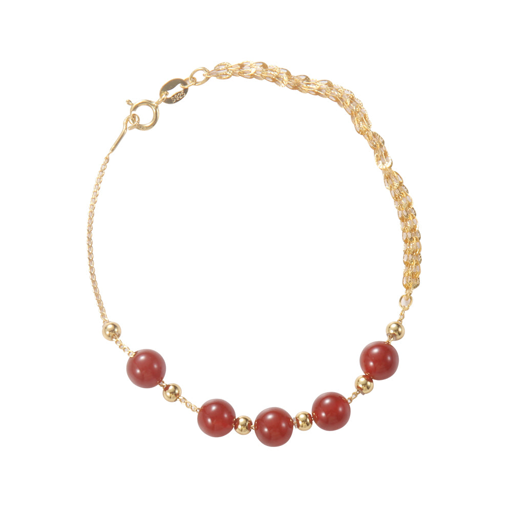 Close-up of red beaded spiritual bracelet, highlighting smooth beads and golden accents.