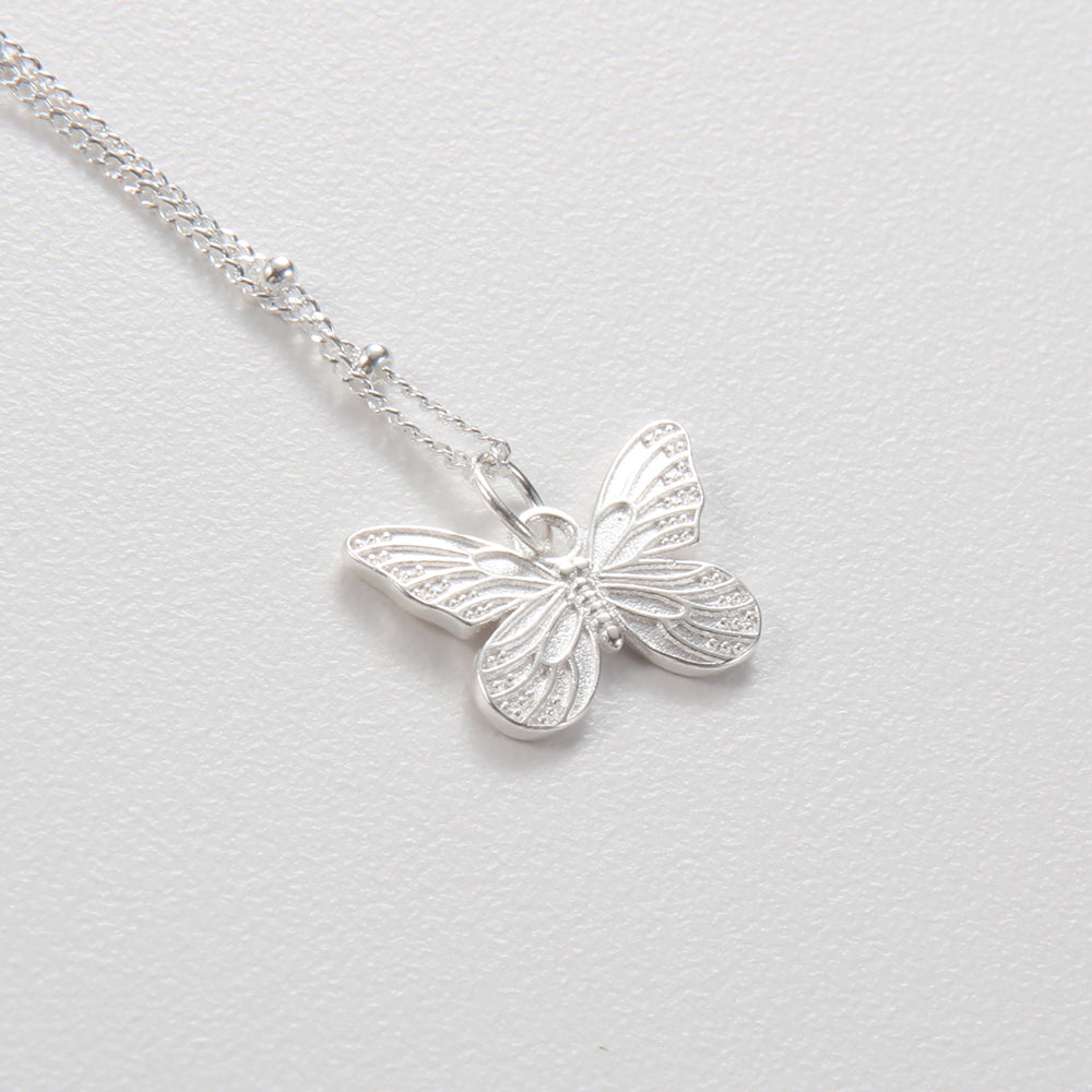 Close-up of the sterling silver butterfly pendant, showing intricate wing details and connecting ring.