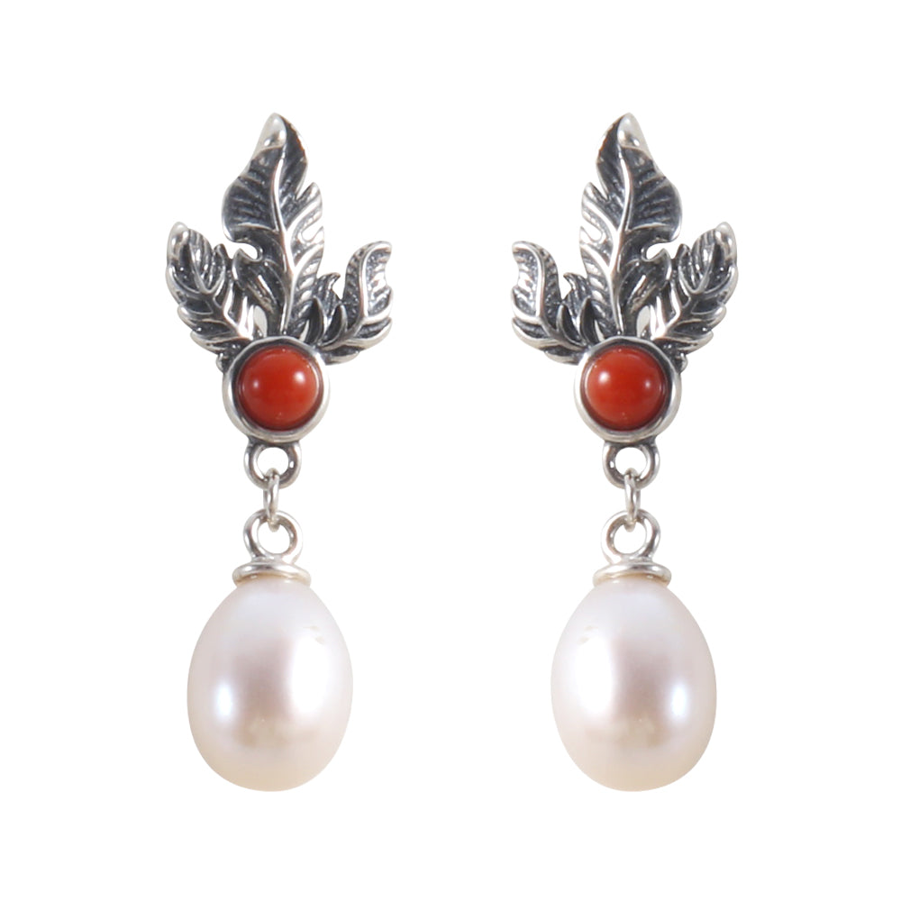 Angled view of sterling silver leaf red gemstone and pearl drop earrings.