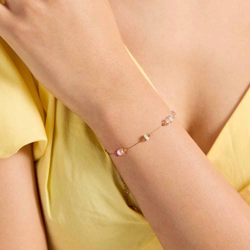 Close-up of woman wearing dainty colorful beaded gold chain bracelet, perfect fit for everyday style.