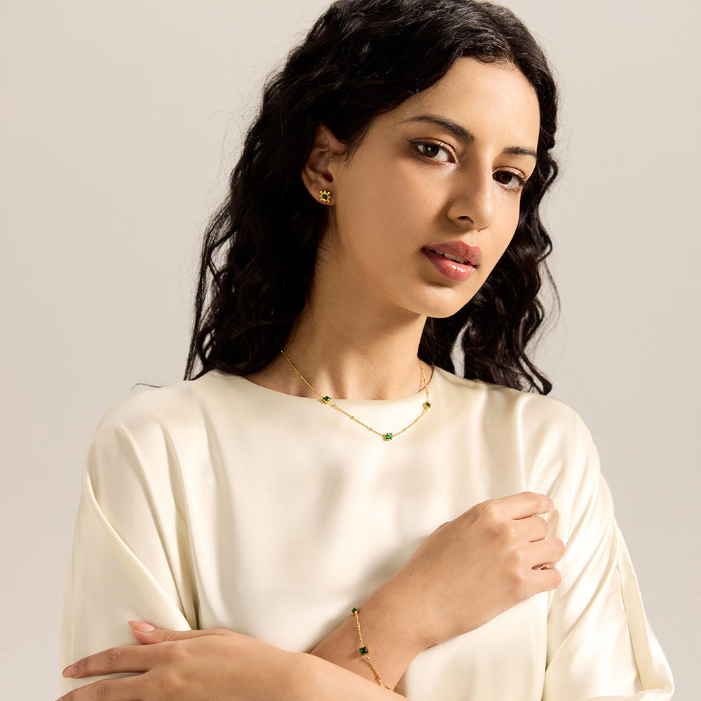 Model showcasing gold chain necklace with square green gemstones, completing a sophisticated look.
