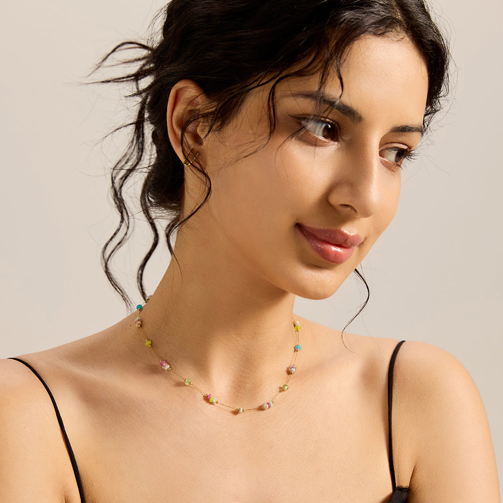 Model showcasing dainty gold chain necklace with multicolor stone beads, complementing a chic look.