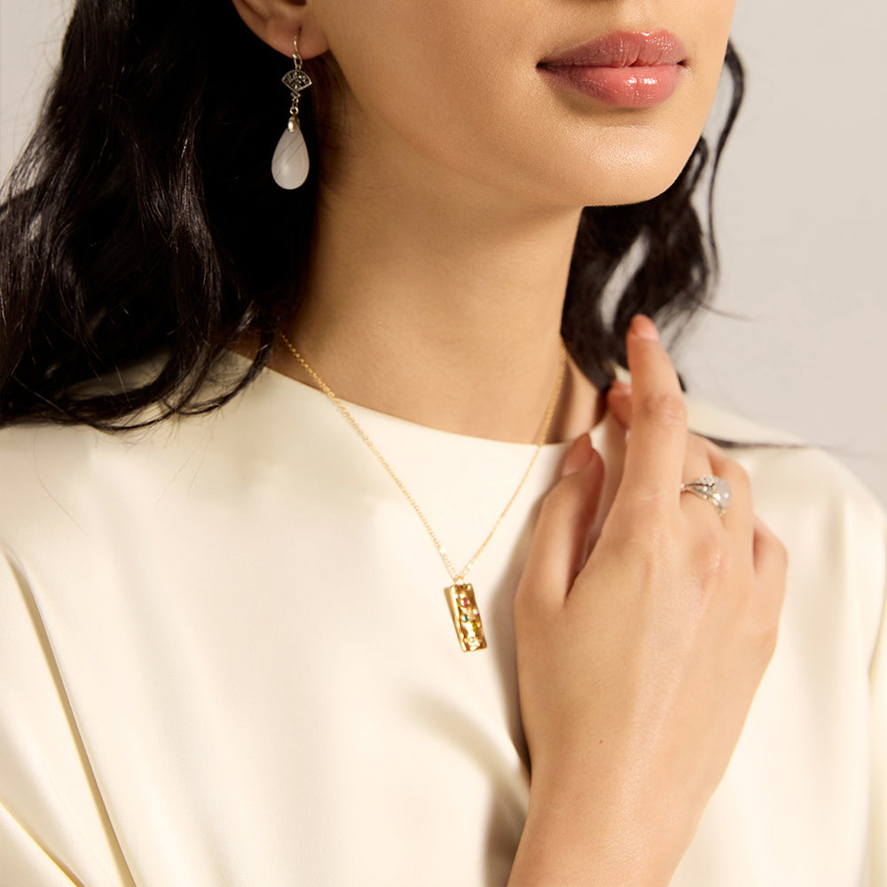 Model wearing gold tone textured rectangle necklace with chakra crystals, complementing a spiritually aligned outfit.