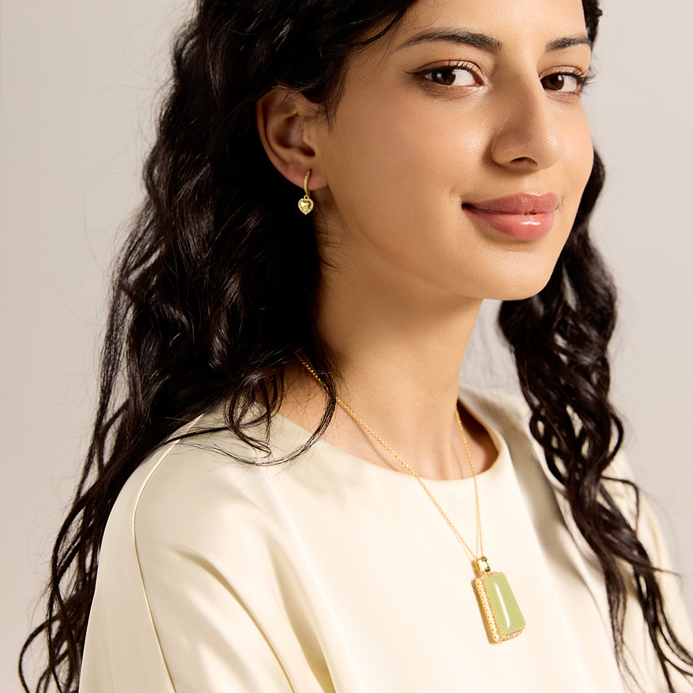 Model showcasing gold tone rectangle green gemstone necklace, complementing a sophisticated outfit.