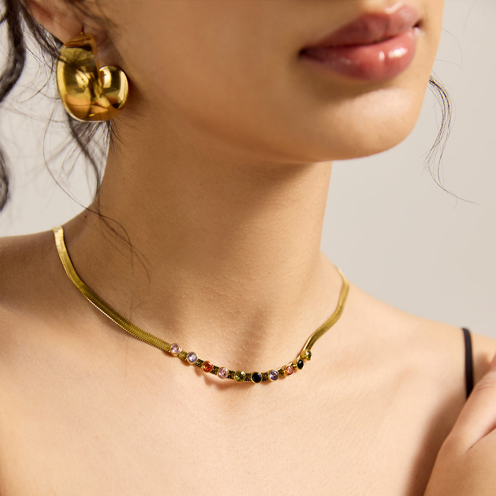 Model showcasing gold snake chain necklace with multicolor gemstones, complementing a chic look.