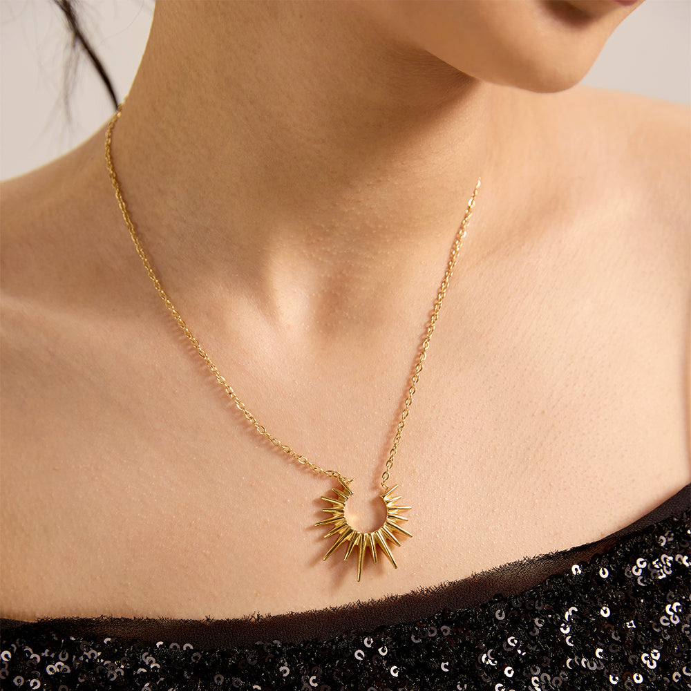 Close-up of woman wearing radiant gold tone sunburst pendant necklace, highlighting its striking design.
