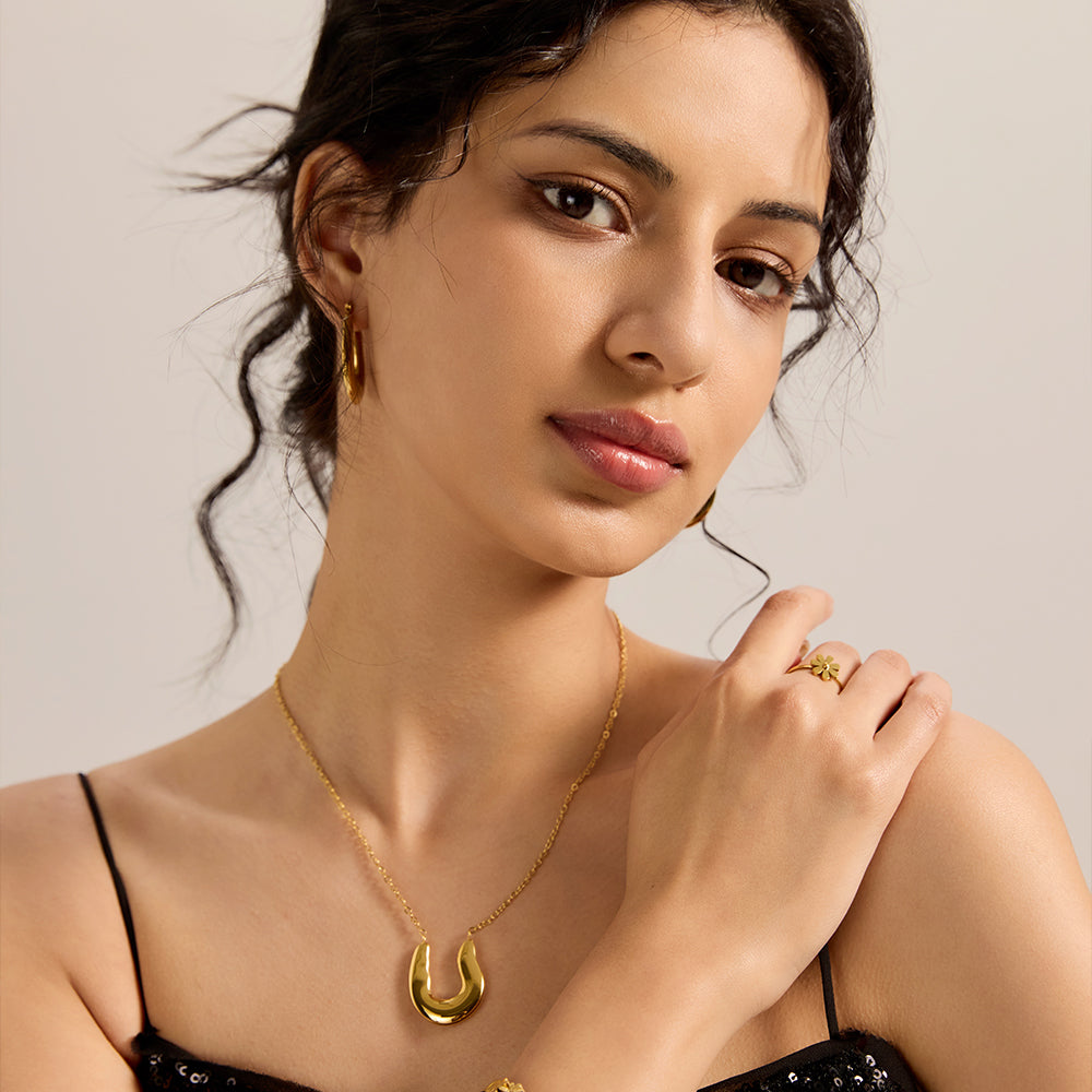 Close-up of woman wearing gold tone polished U-shape pendant necklace, highlighting its sleek design.