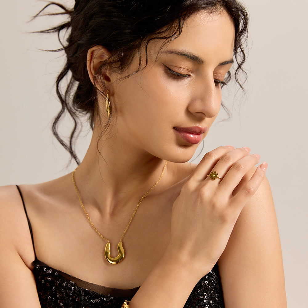 Model wearing modern gold U-shape pendant necklace with matching accessories, showcasing an elegant outfit.