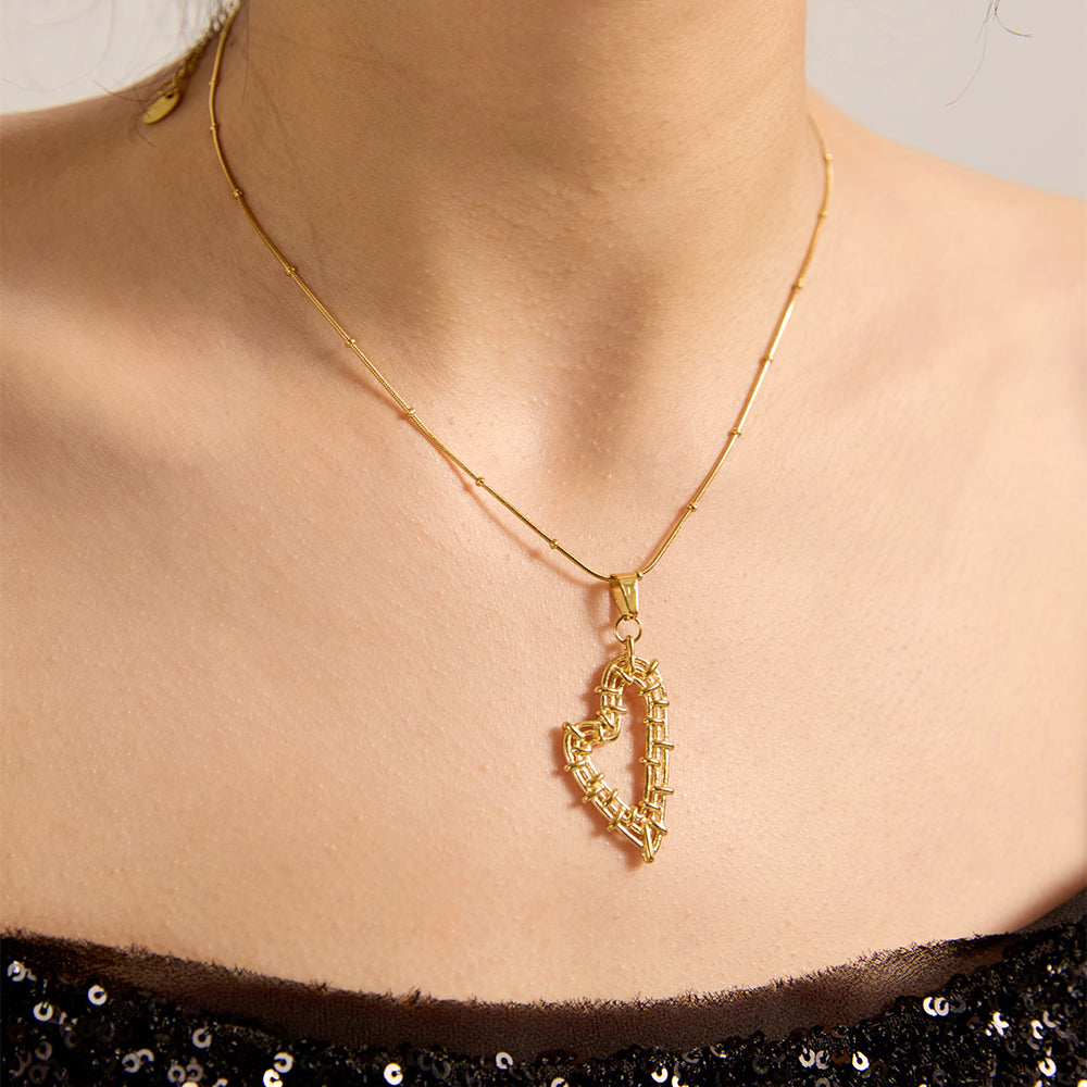Close-up of woman wearing gold tone wire-wrapped heart pendant necklace, highlighting its unique design.