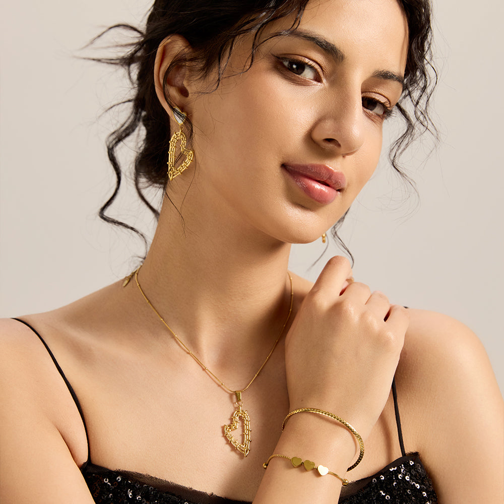 Model wearing gold tone wire-wrapped heart pendant necklace with matching earrings and bracelet, completing an elegant look.