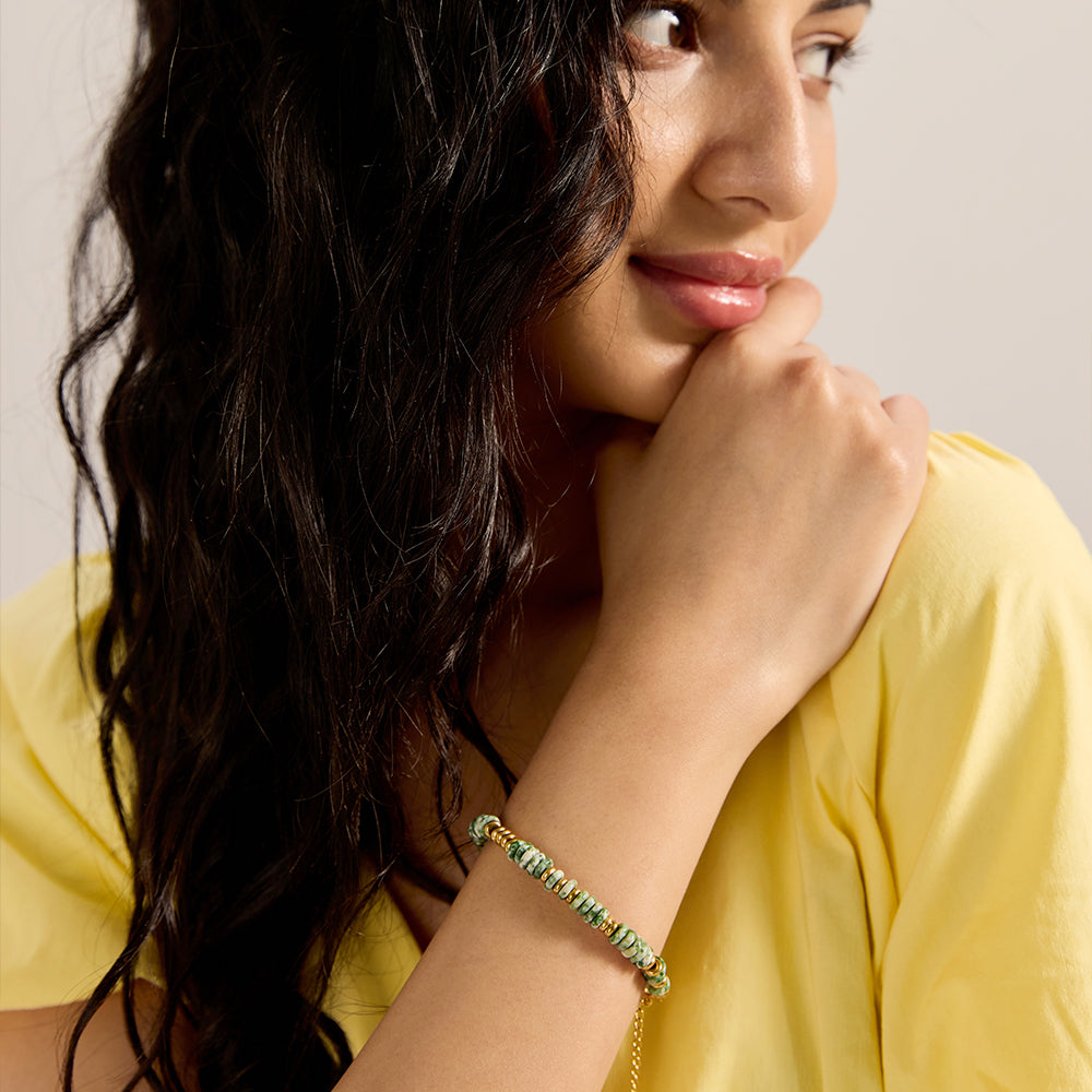 Model wearing dainty green stone and gold bead bracelet, showcasing its fit and style.