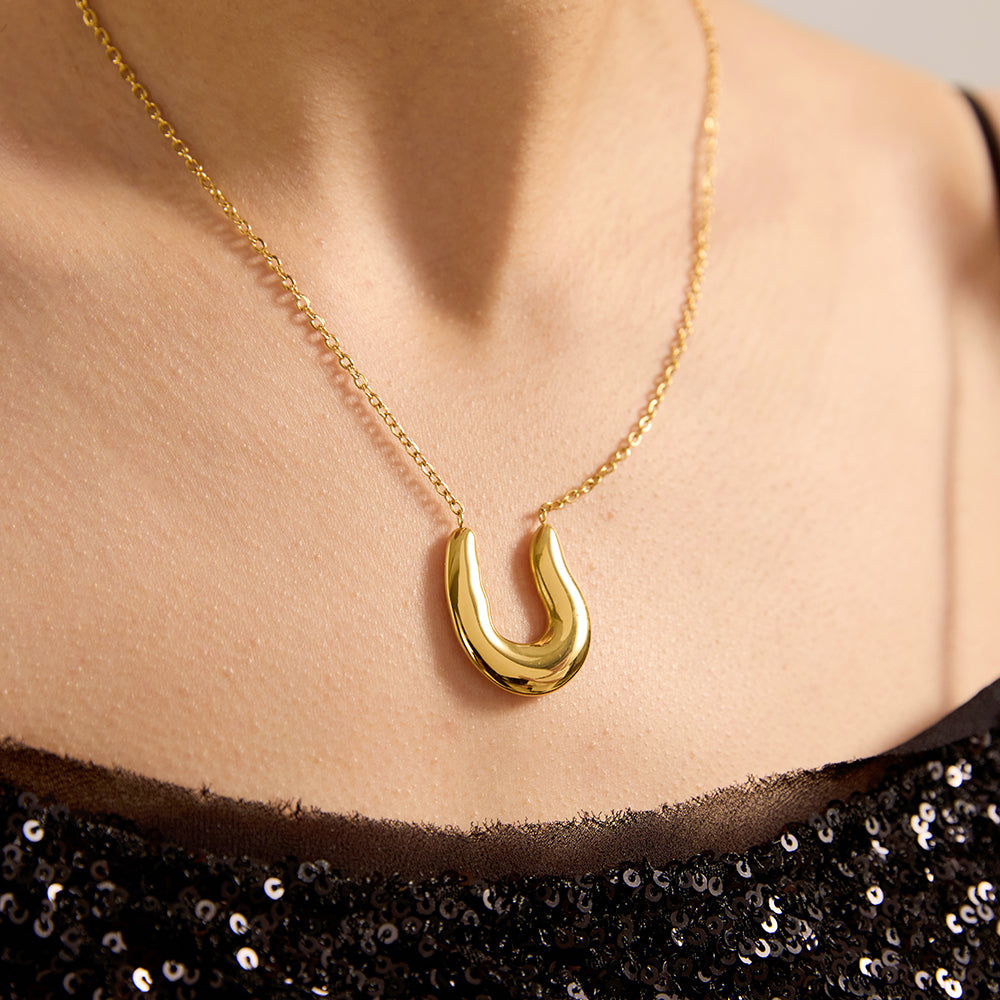 Model showcasing gold tone polished U-shape pendant necklace, complementing a chic and sophisticated look.