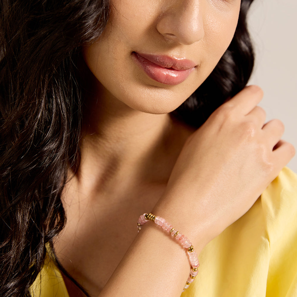 Model wearing dainty pink stone and gold bead bracelet, showcasing its fit and style.