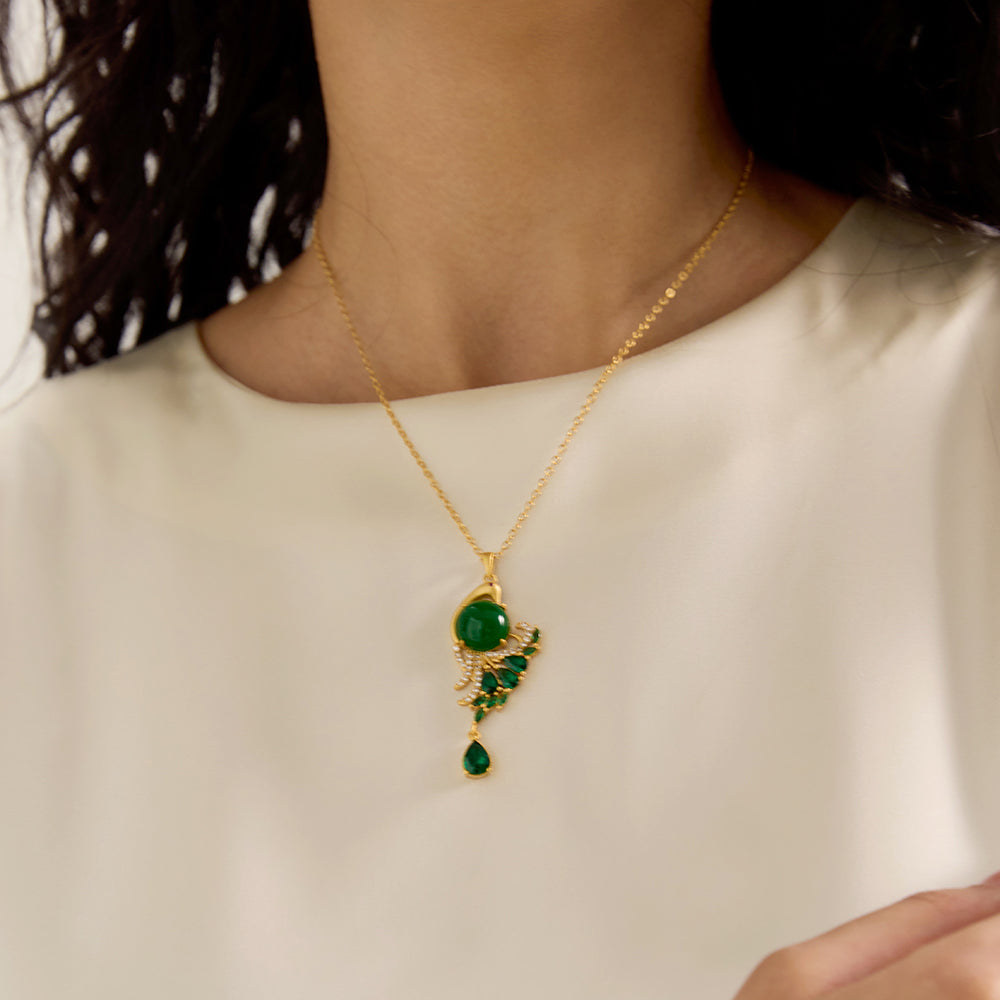 Close-up of woman wearing spiritual gold tone peacock green gemstone amulet necklace, highlighting its intricate design.