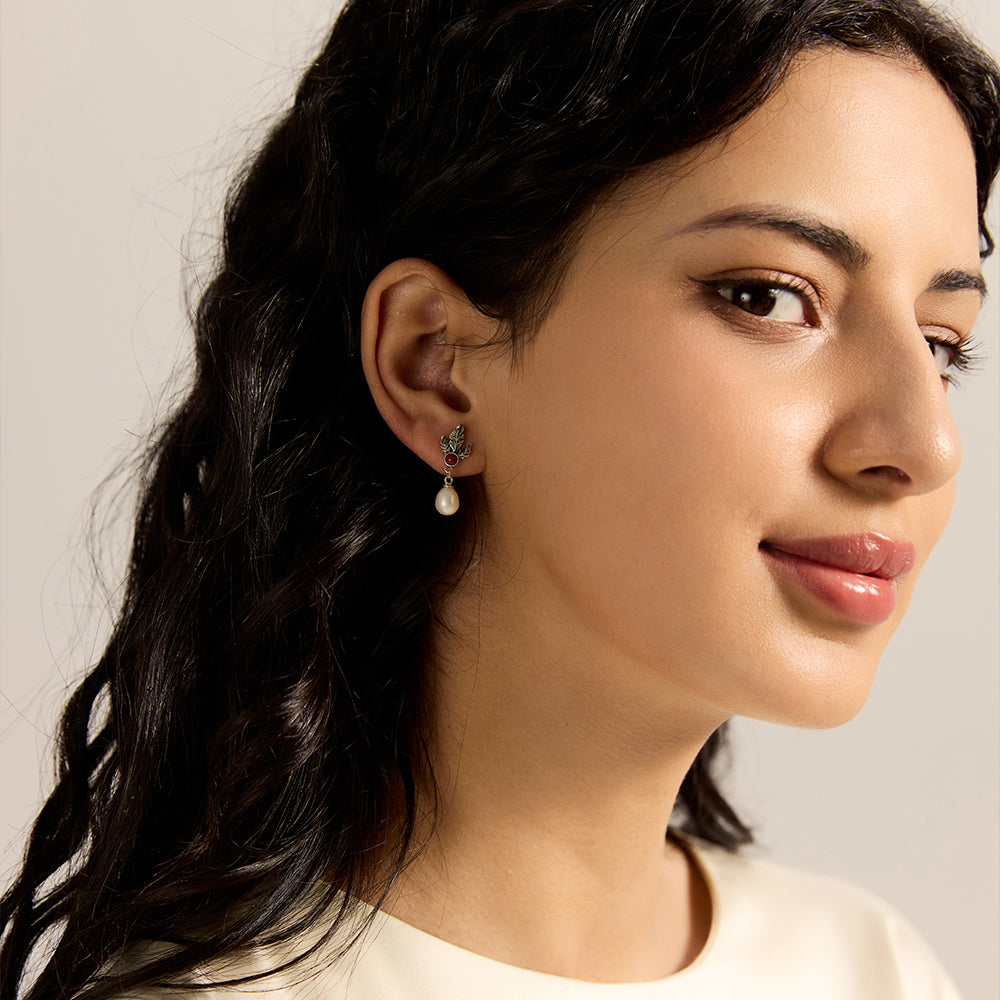 Model showcasing sterling silver leaf red gemstone and pearl drop earrings, complementing her style.